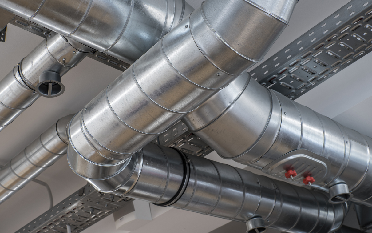 Installed galvanised spiral ventilation ductwork with an access hatch and inspection ports above a ceiling