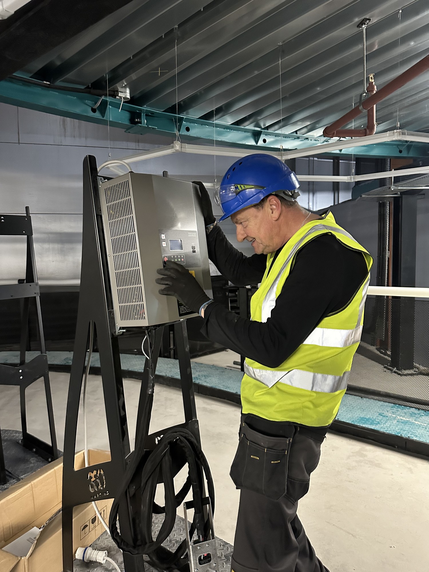 Engineer in high visibility vest and hard hat commissioning a wall mounted control unit on site