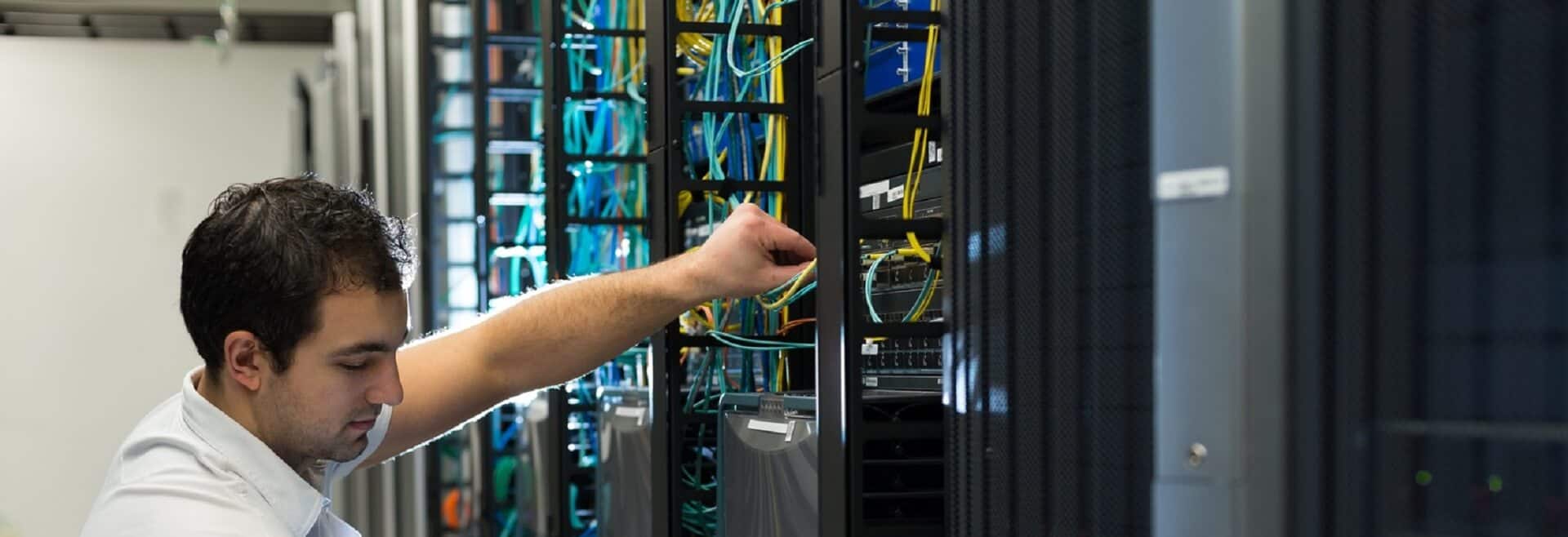 Engineer testing structured data and fibre cabling in high-density server racks